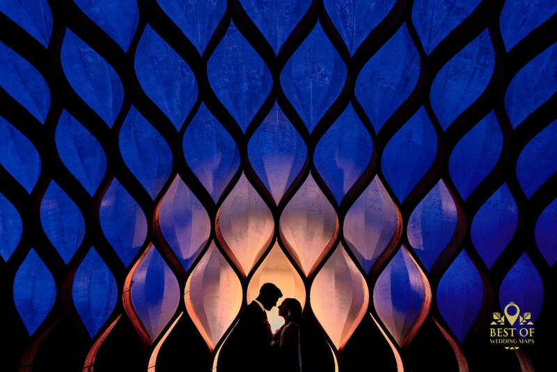 Silhouetted couple kissing against warm-lit architectural backdrop with blue patterned overlay.