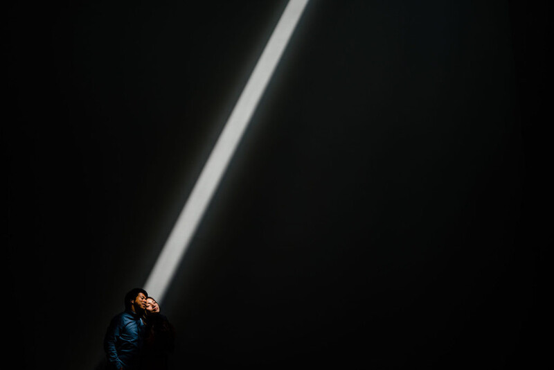 Person silhouetted against a dramatic beam of light against a dark background.