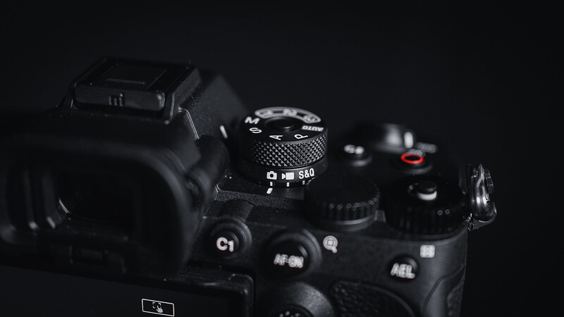 Professional camera with lens and accessories arranged on dark surface with dramatic lighting.