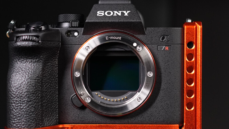 Sony a7R mirrorless camera body with E-mount displayed against black background alongside red vertical light panel.