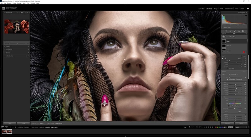 Portrait of a woman with dramatic black headwear and colorful feather accessories, gazing upward with hand near face.