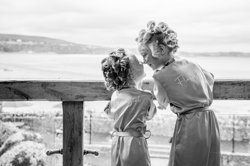 Two children viewed from behind using binoculars to look out at a lake and distant shoreline.