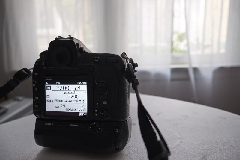 DSLR camera displayed on a table showing exposure settings on its rear LCD screen.