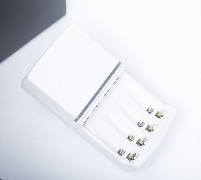 White device with blank display panel and six metallic connectors arranged in two rows on right side.