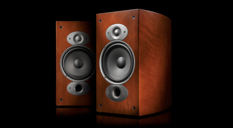 Pair of wooden bookshelf speakers with multiple drivers against a black background.