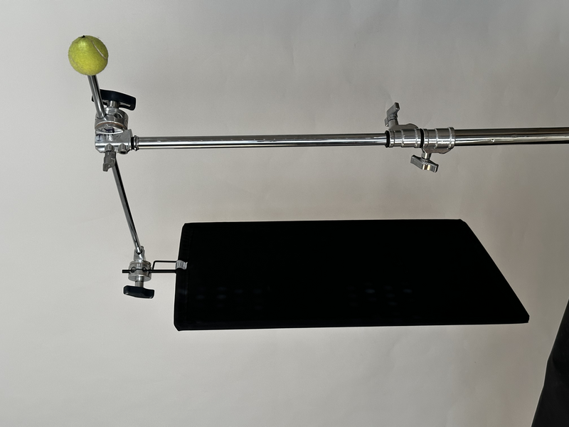DIY photography lighting rig with ball clamp and articulating arm mounted on black platform.
