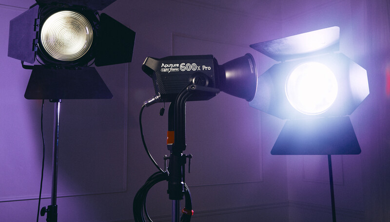 Three professional studio lights with Fresnel lenses arranged in a purple-lit studio setup.