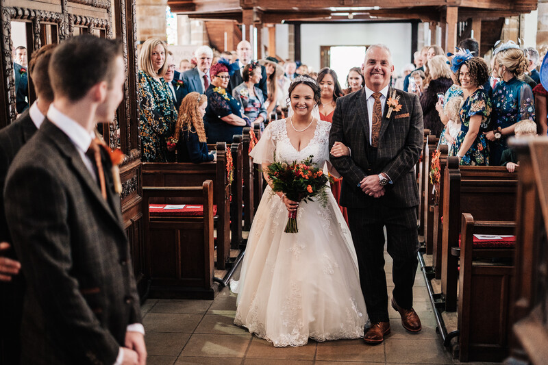 Bride and groom walking down the aisle of a wooden church during their wedding ceremony.