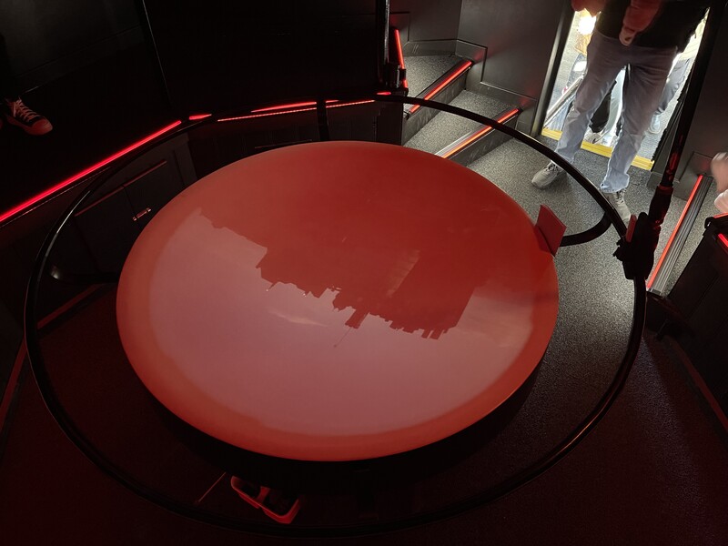 Red circular display with neon lighting against dark background.