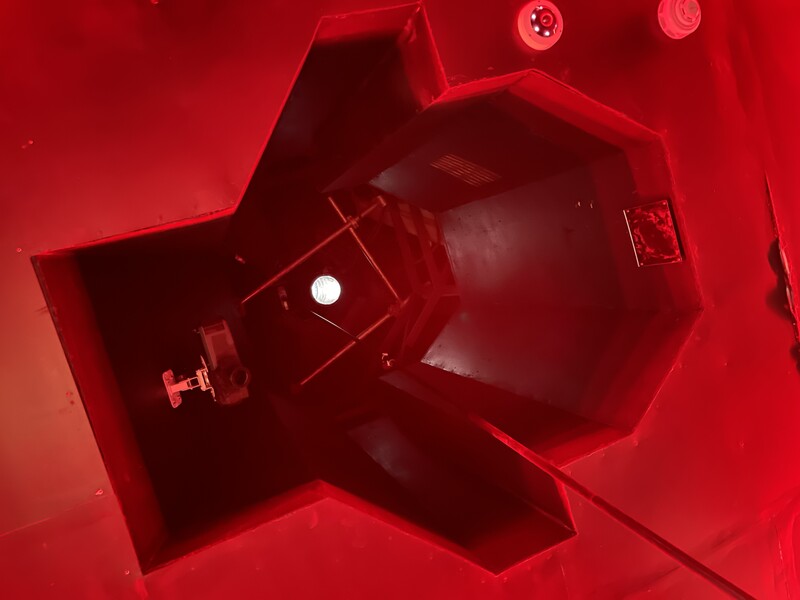 Red studio setup photographed from above, showing lighting equipment and reflective surfaces against monochromatic backdrop.
