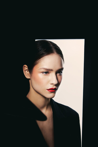 Woman with dark hair and red lipstick against geometric black and white background.