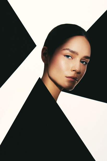 Woman's face positioned off-center against geometric black and white triangular background shapes.