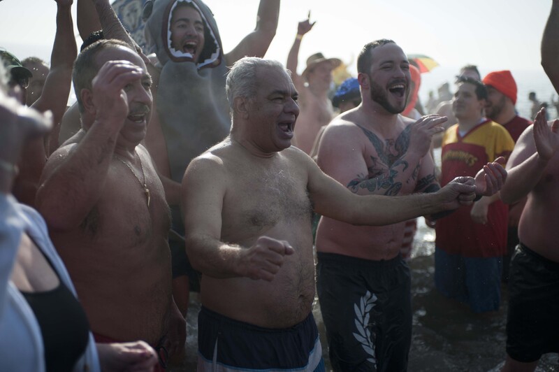 Group of shirtless men celebrating together outdoors in bright daylight.