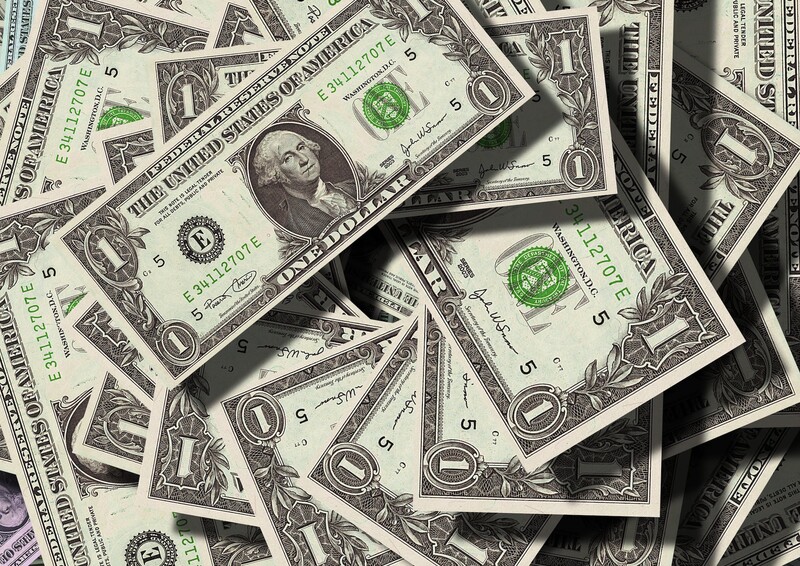 Scattered U.S. one dollar bills arranged in an overlapping flat lay composition.