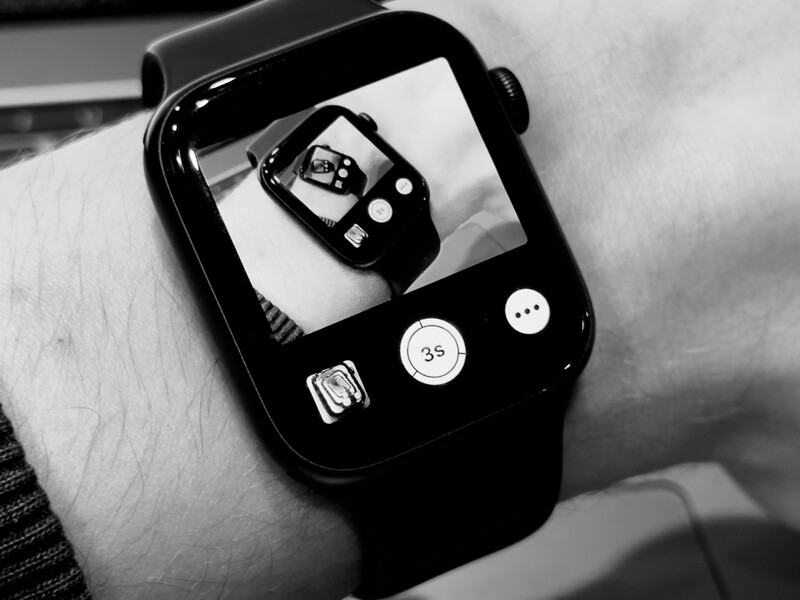 Smartwatch on wrist displaying its interface with app icons visible on the screen.