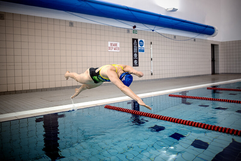 Swimmer diving into an indoor competition pool during a training session.