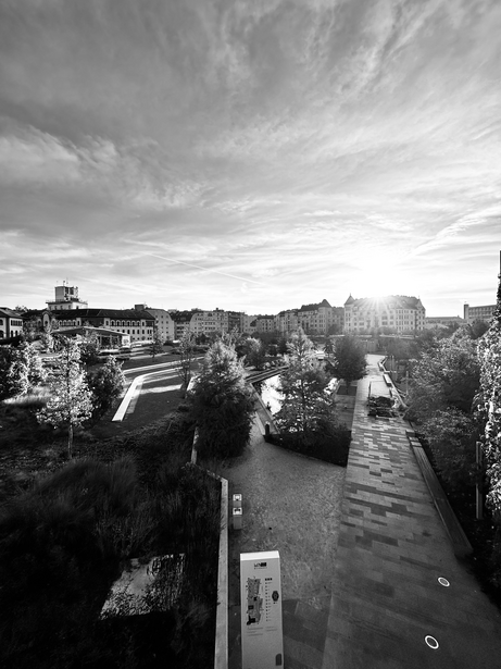 Black and white aerial view of a waterway running through a dense urban cityscape with buildings and streets.