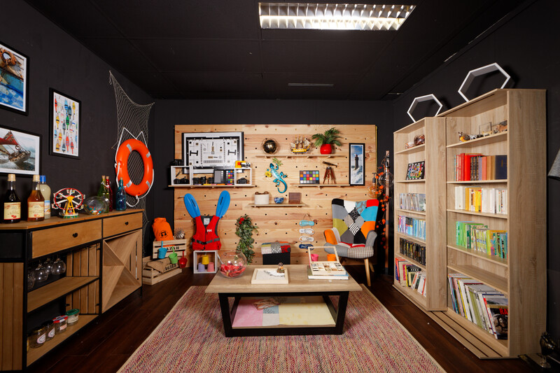 A colorful creative studio with wooden storage, pegboard wall organization, and a central work table.