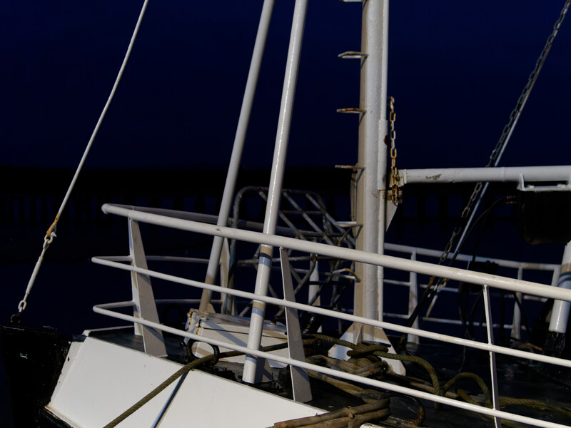 Nighttime detail of a sailboat's rigging and metal framework against dark sky.