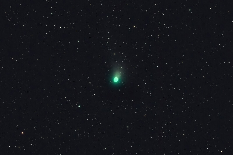 Bright green comet or celestial object centered against a dark starfield.