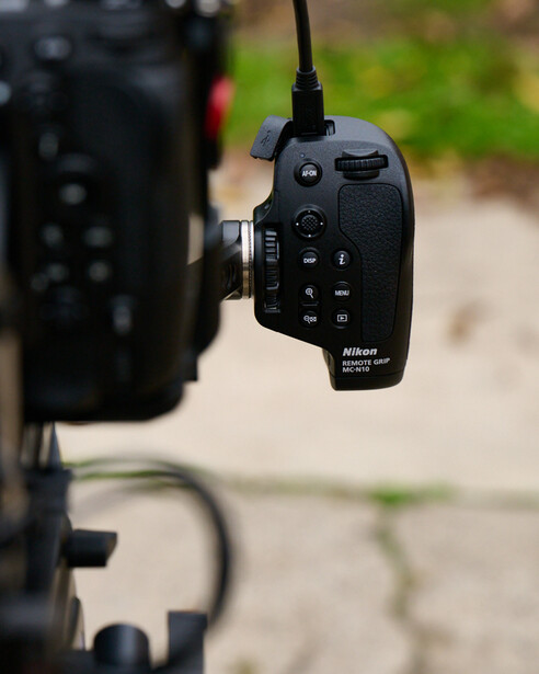 Nikon wireless remote control mounted on camera rig with blurred equipment in background.