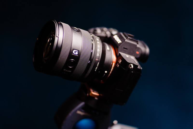 Sony mirrorless camera with wide-angle lens mounted, photographed against dark blue background.