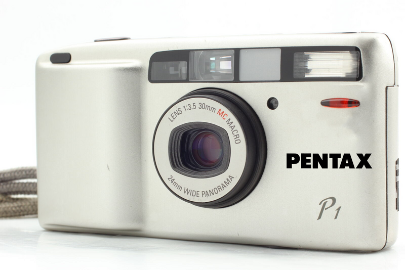 Pentax P1 compact film camera with 35mm lens and built-in flash against white background.