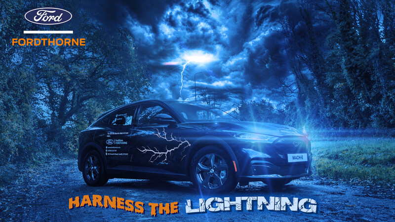 Dark blue electric vehicle parked on a forest road beneath a dramatic lightning storm sky.