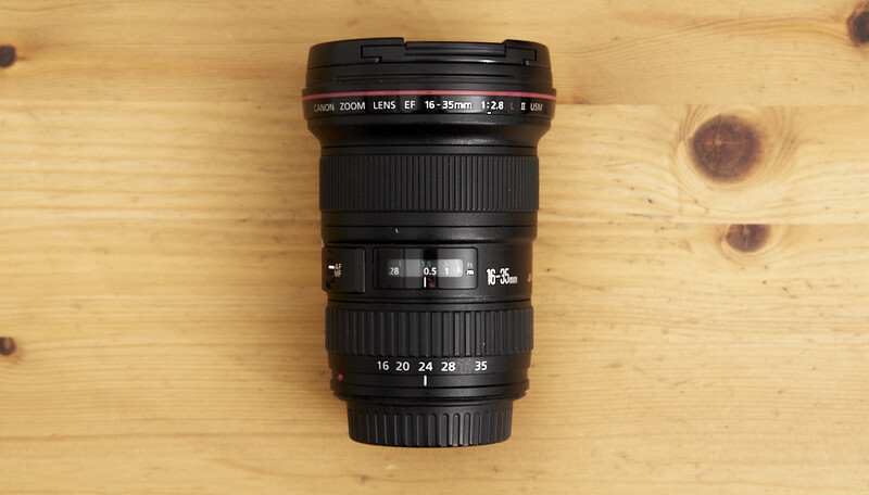 Canon EF 16-35mm f/2.8L zoom lens on wooden surface.