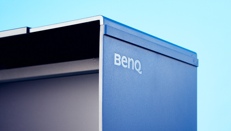 Close-up of a blue BenQ monitor against a clear light blue background.