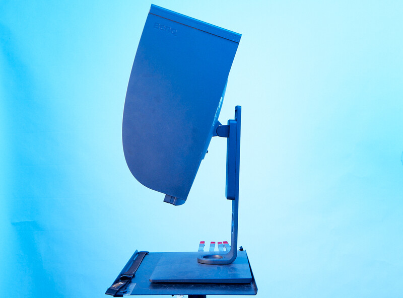 Blue studio lighting reflector mounted on a stand against a light blue background.