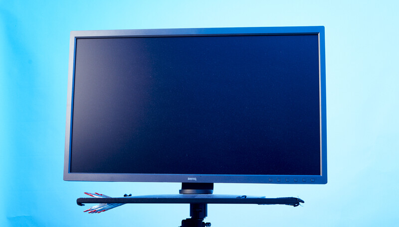 Dell monitor with blue bezels displaying a dark screen against a light blue background.