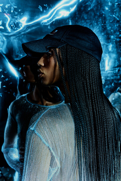 Person wearing a black cap and light-colored shirt silhouetted against vivid blue electric energy and light effects.