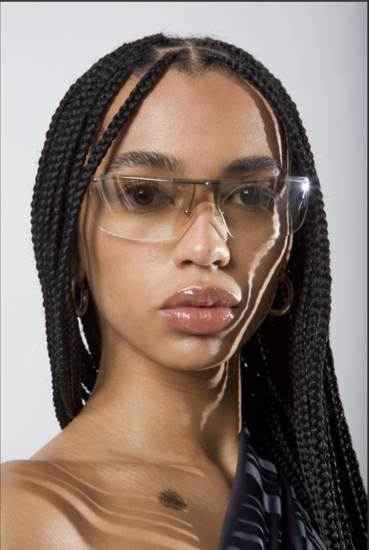 Portrait of a person wearing clear-framed glasses and earbuds against a neutral background.