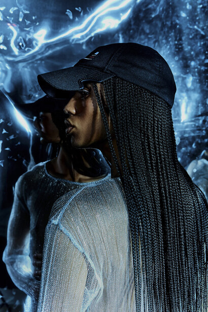 Person in profile wearing a black cap and light-colored shirt with braided hair, surrounded by electric blue energy effects.