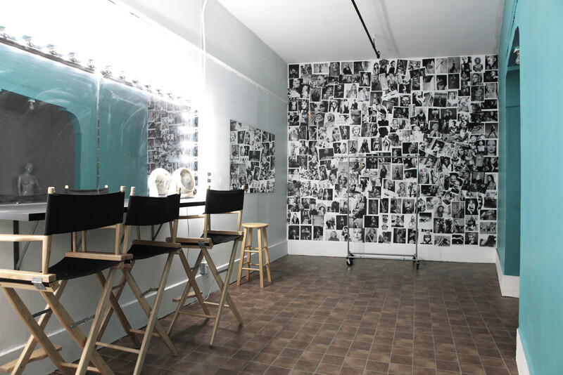 Modern studio space with turquoise accent walls, director's chairs, and floor-to-ceiling photo collage wall.