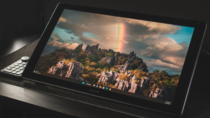 Tablet displaying a landscape photograph of rocky mountains with dramatic sky and rainbow.