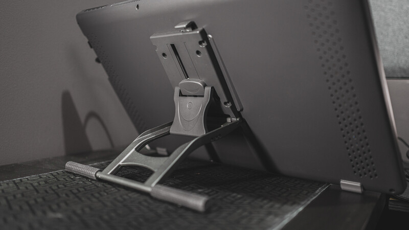 Tablet computer mounted on an articulating stand positioned behind a laptop keyboard on a desk.