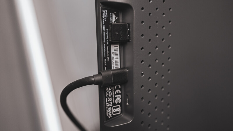 Close-up of a power adapter cable plugged into the back of electronic equipment with perforated metal casing.