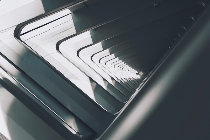 Stack of open notebooks with curved pages creating a geometric pattern of diminishing white and dark sections.