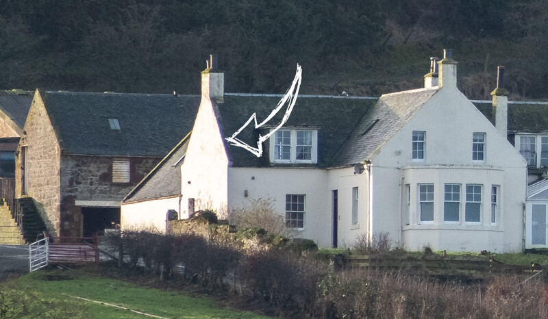 White cottage with distinctive curved roof alongside stone buildings in a rural Scottish setting.