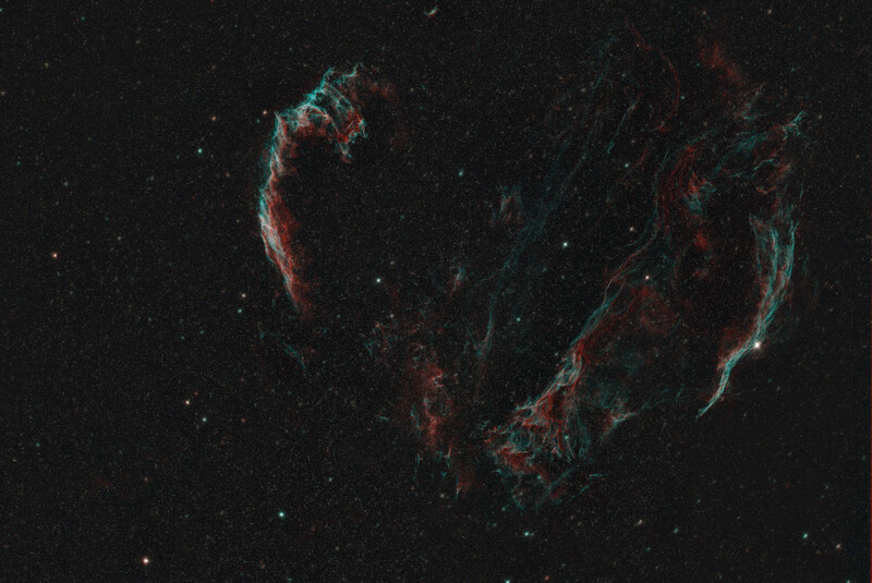 Cygnus Loop nebula remnant displaying wispy red and cyan filaments against a starfield.