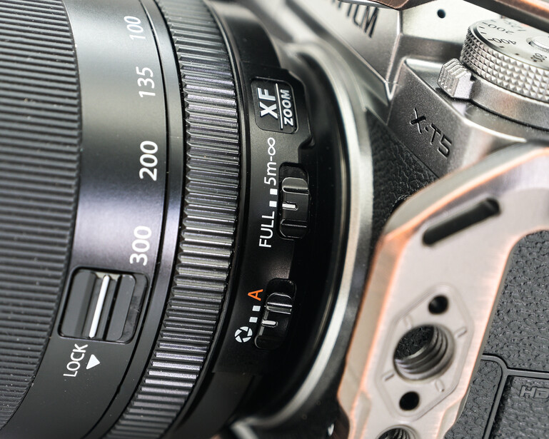 Close-up of a camera lens showing focal length markings from 200 to 35mm and focus ring details.