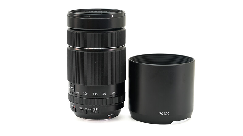 Telephoto zoom lens with lens hood positioned side-by-side against white background.
