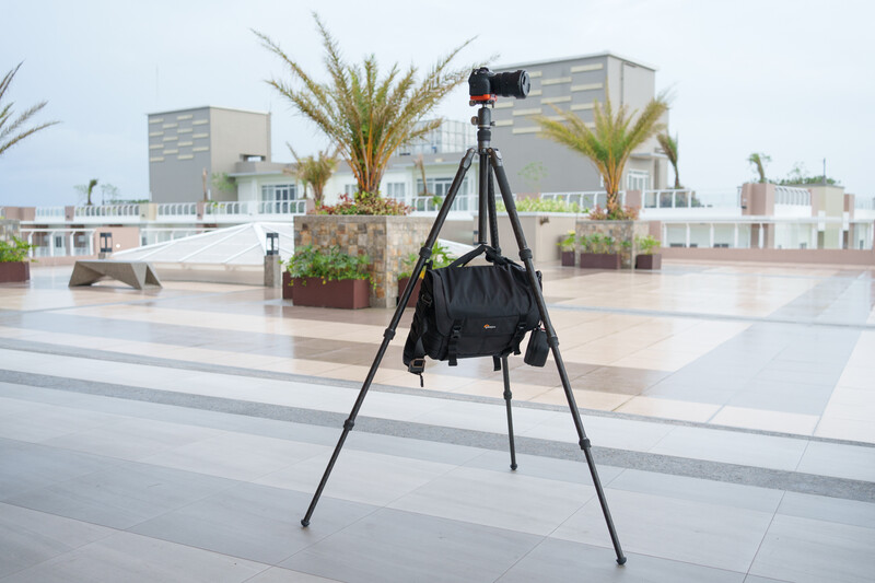 Professional camera mounted on tripod with black weather cover on rooftop location.