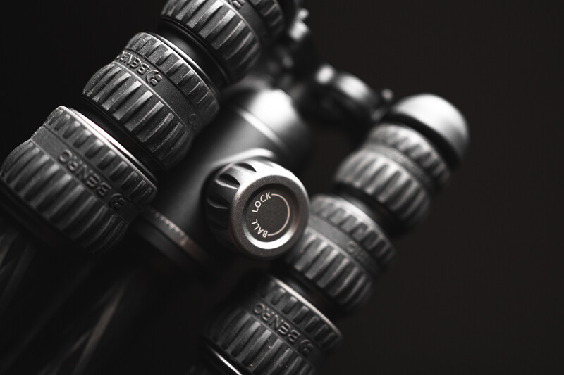 Collection of vintage camera lenses arranged diagonally against a dark background in black and white.