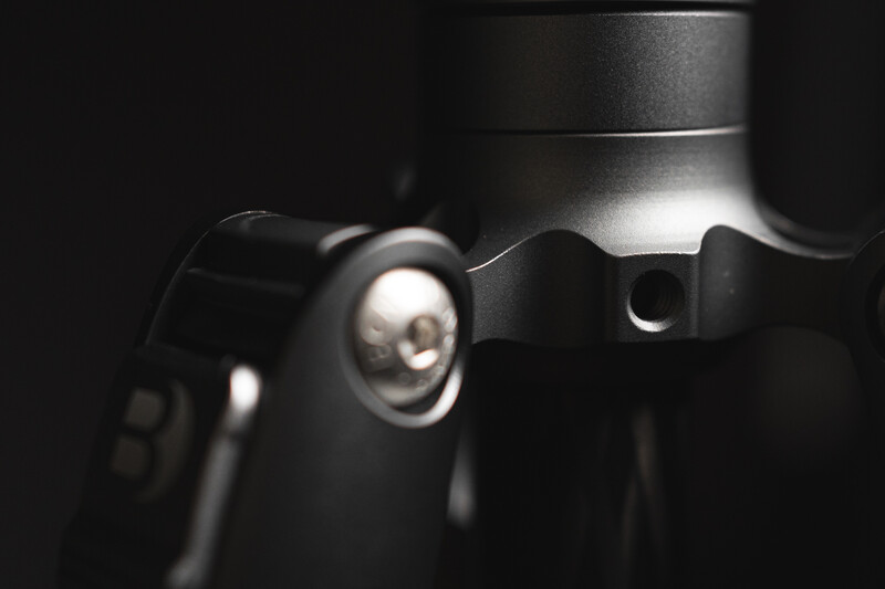 Close-up of a camera lens element and mechanical components illuminated by dramatic side lighting against a dark background.