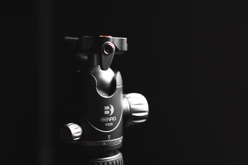 Benro ball head tripod mount with adjustment knobs against dark background.