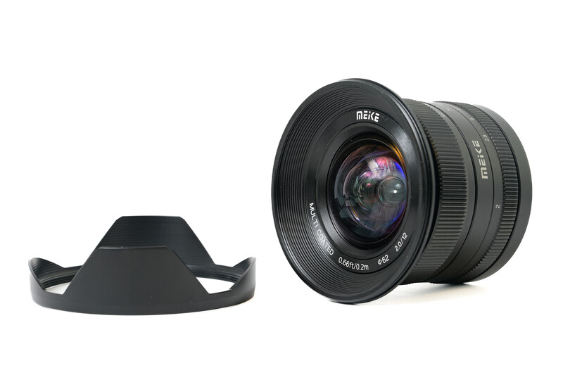 Meike 12mm f/2.8 ultra-wide lens with matching lens hood displayed separately.