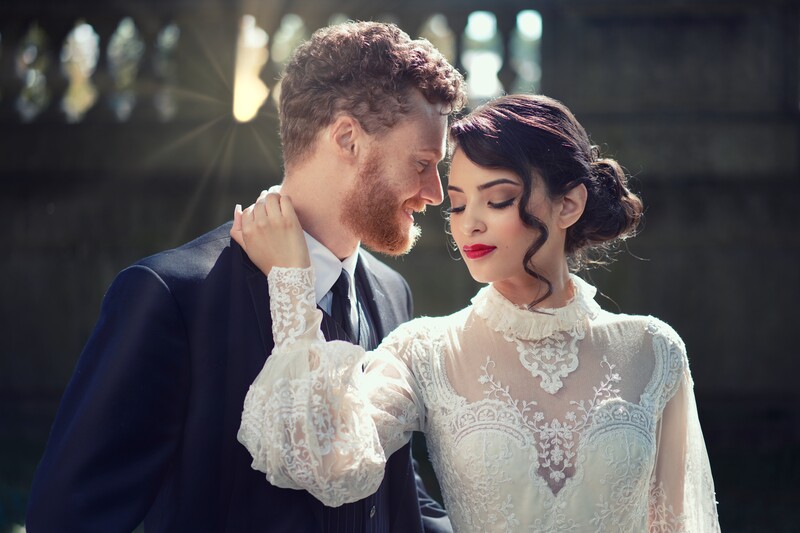 Bride and groom in formal wedding attire sharing an intimate moment indoors.